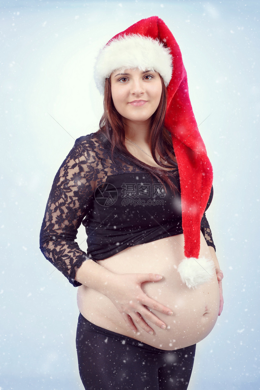 怀着小肚子的漂亮怀孕的圣塔孕妇成人母亲腹部生活微笑帽子女士女孩下雪婴儿图片