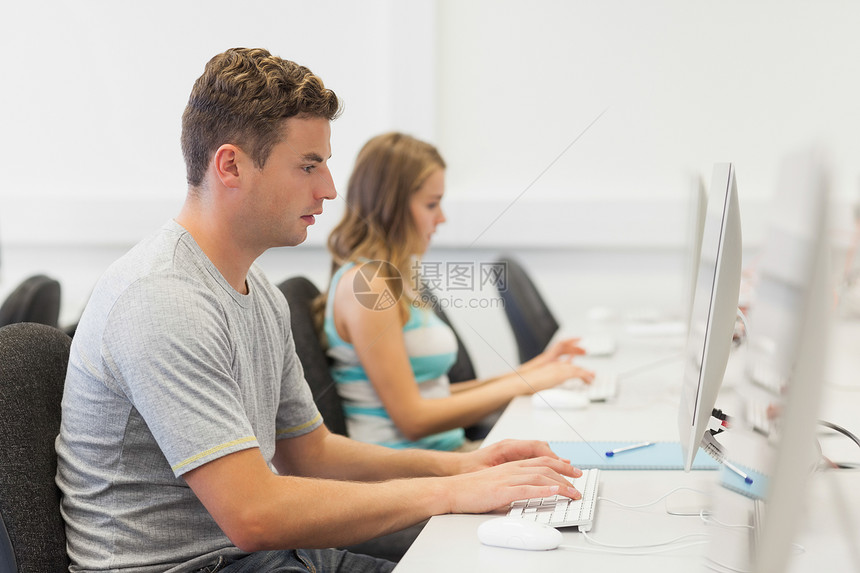 两名在电脑上单独工作认真的大学生;图片