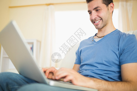 坐在沙发上看笔记本电脑的有外在吸引力的男人背景图片