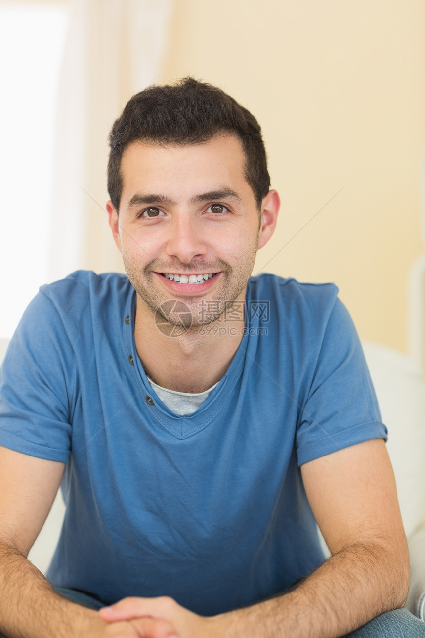 男人在沙发上放松闲暇男性微笑公寓衬衫住所房子快乐蓝色家庭图片