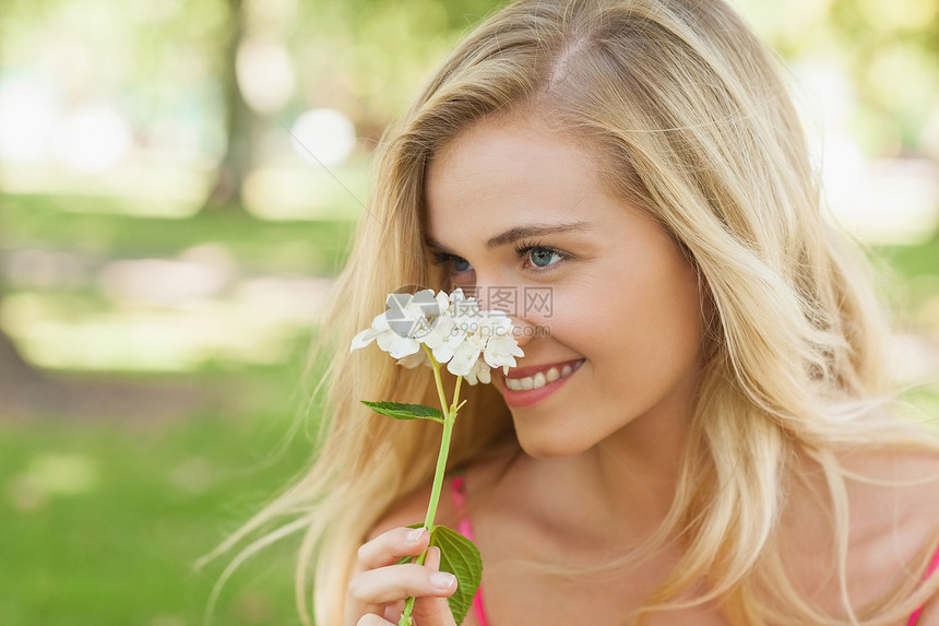 年轻女人闻着白花的香味图片