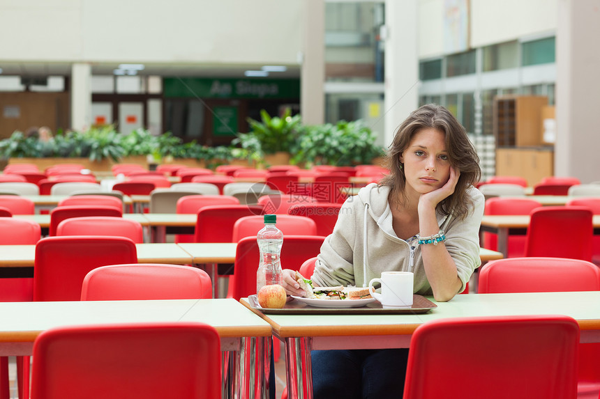 坐在食堂里拿着餐盘的可悲学生头发教育餐厅短发椅子托盘大学杯子悲伤饮料图片