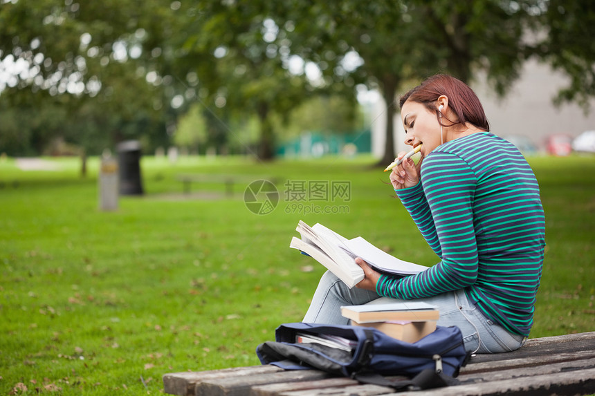 坐在长椅上读书的有想象力的随意学生图片