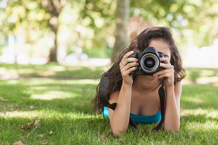 在草坪上躺着拍摄照片的 黑发女人前视线高清图片