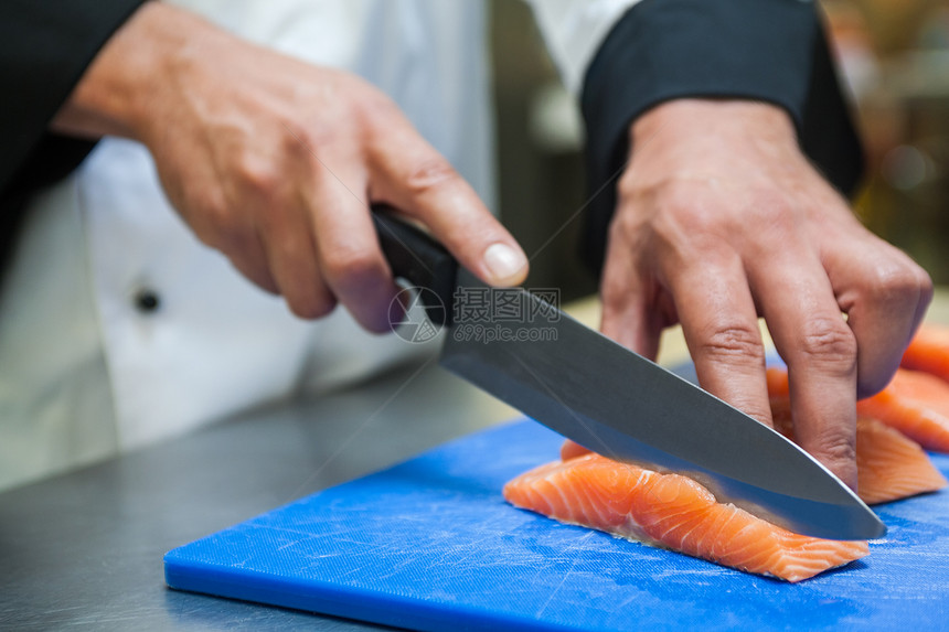 厨师用尖刀切鲑鱼的近距离图片