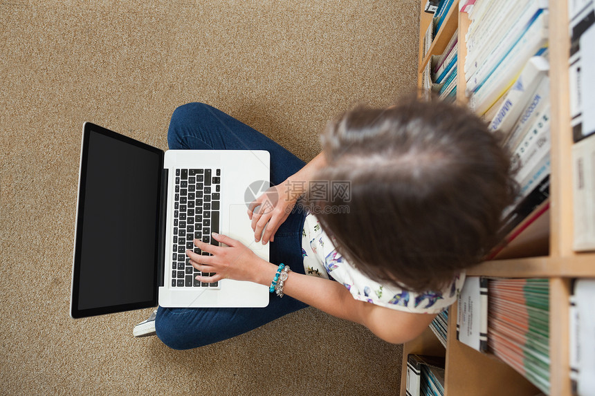 学生在图书馆楼层使用笔记本电脑反对书架房间地面专注网络智慧教科书知识女性键盘短发图片
