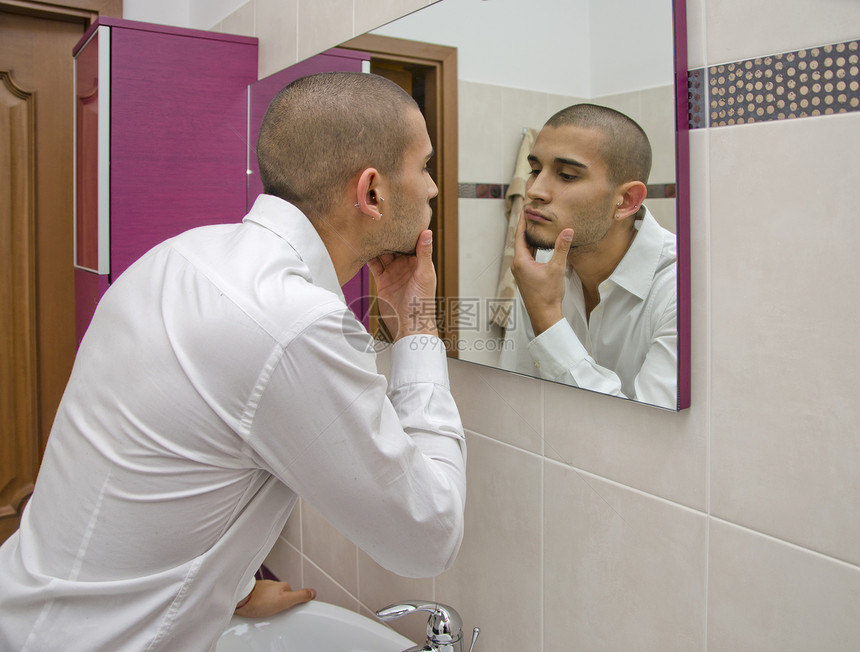 英俊的年轻人看着自己 在浴室镜子里男性外貌成人后水反射卫生图片