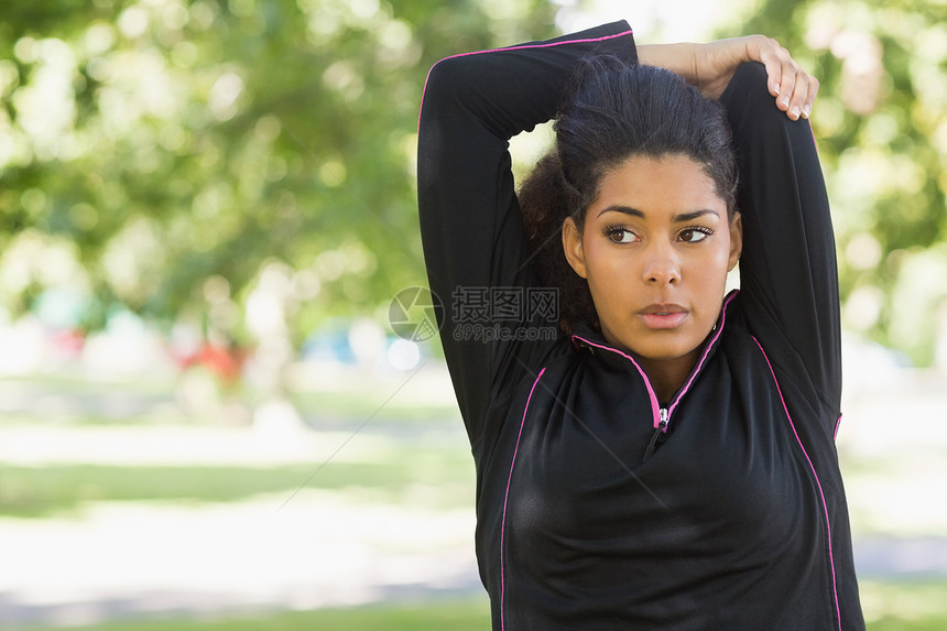 女人在公园运动时伸手拉手活动体力闲暇活力锻炼树木混血拉伸护理运动服图片