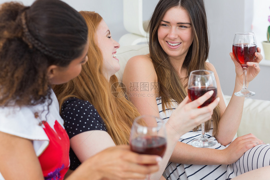 带着葡萄酒杯的快乐朋友 享受谈话愉快金发女郎沙发睡衣金发讨论酒精友谊朋友们幸福棕色图片