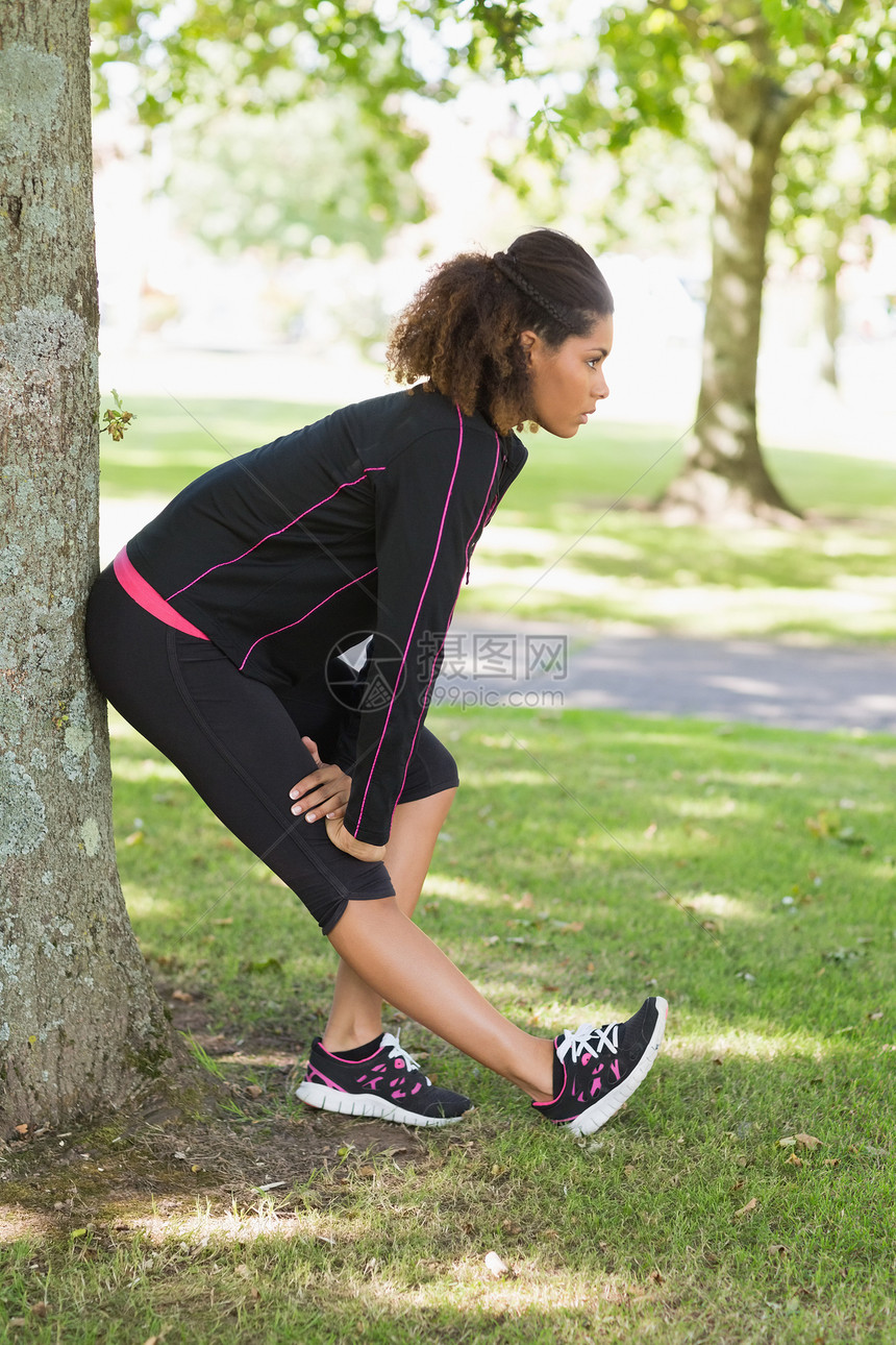 健康妇女在公园锻炼期间伸展腿部树木头发活力生活方式拉伸女性护理训练活动身体图片
