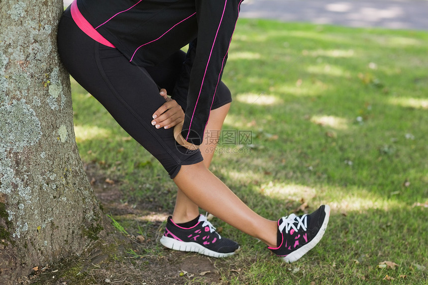 在公园锻炼期间 低层妇女伸展腿部图片