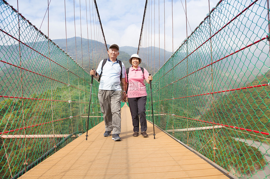 在自然公园的桥上走着快乐的老年情侣家庭国家冒险享受男性微笑男人夫妻森林远足图片
