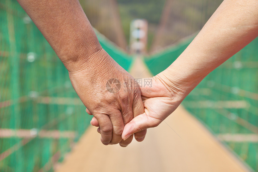 男高年男子和女高龄男子夫妇手牵手走在草地上图片