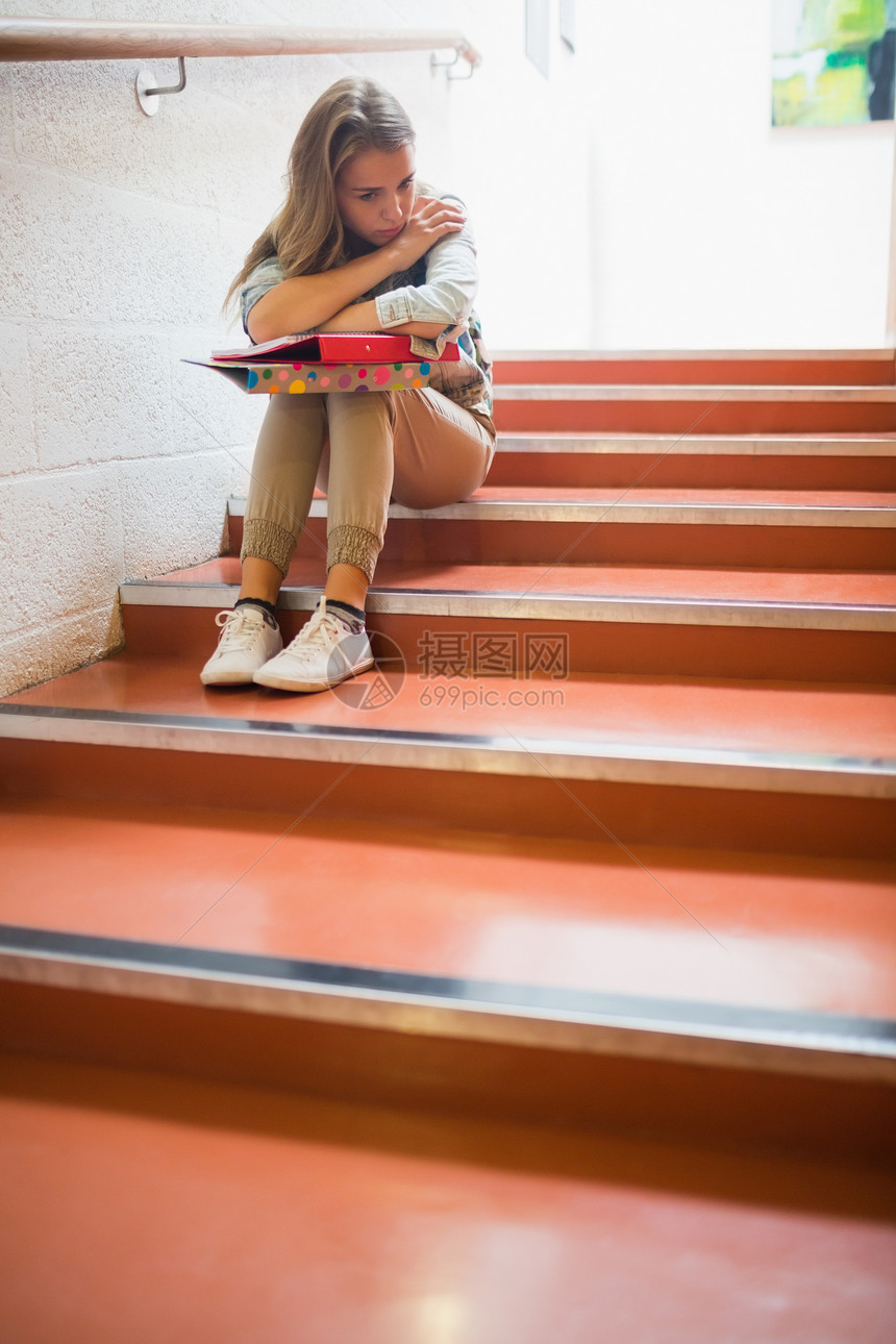 坐在楼梯上的学生心烦悲哀教育女性大厅寂寞愁云图书笔记本脚步红发图片