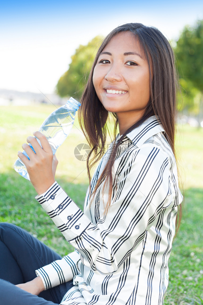 美丽的亚洲女孩在公园里喝水图片