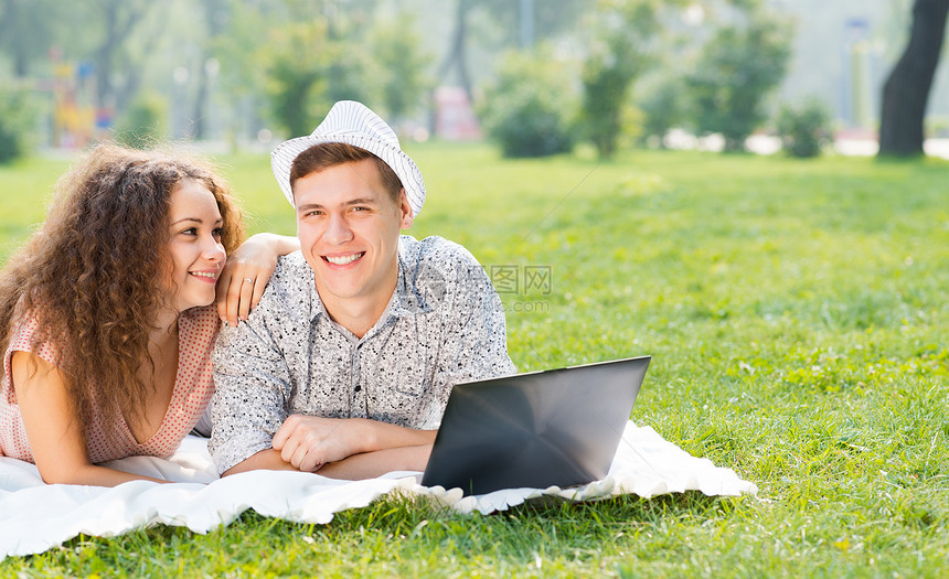 一对夫妇一起躺在公园里 带着笔记本电脑互联网技术商业女性生活青年乐趣快乐微笑男性图片