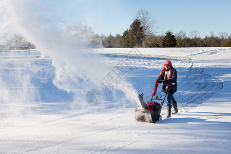 高级妇女与吹雪者清扫车暴风雪机器冷冻投掷者季节人行道车道女士天气机械背景图片