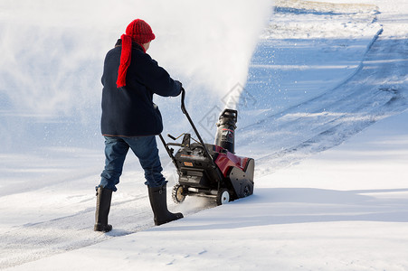 高级妇女与吹雪者清扫车住宅季节冷冻鼓风机暴风雪投掷者人行道机器退休机械背景图片