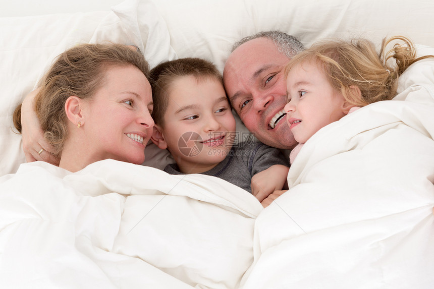 快乐的年轻家庭同床共枕图片