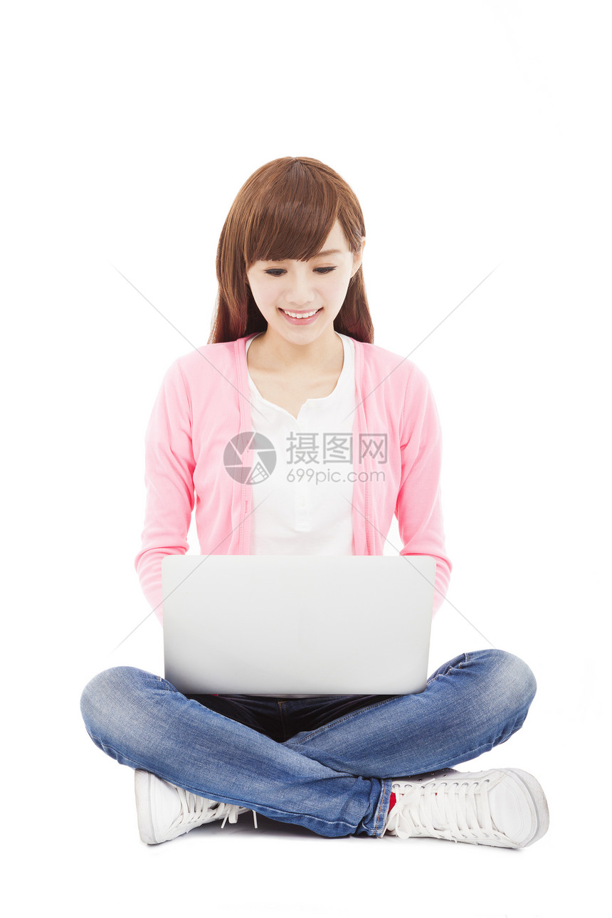 坐在并使用笔记本电脑时微笑的年轻妇女图片