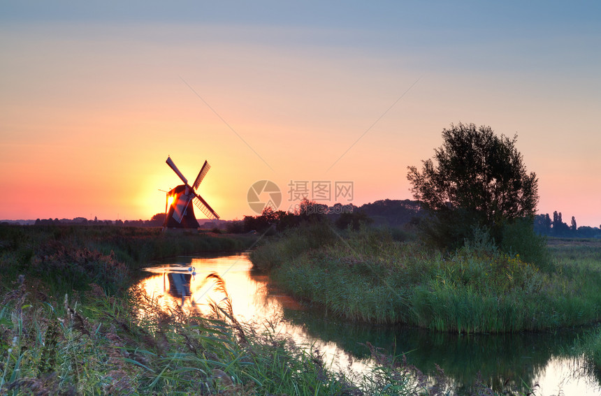 荷兰风车后面有日出和阳光图片