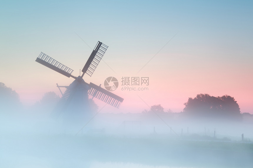 浓密日出雾中迷人的荷兰风车图片