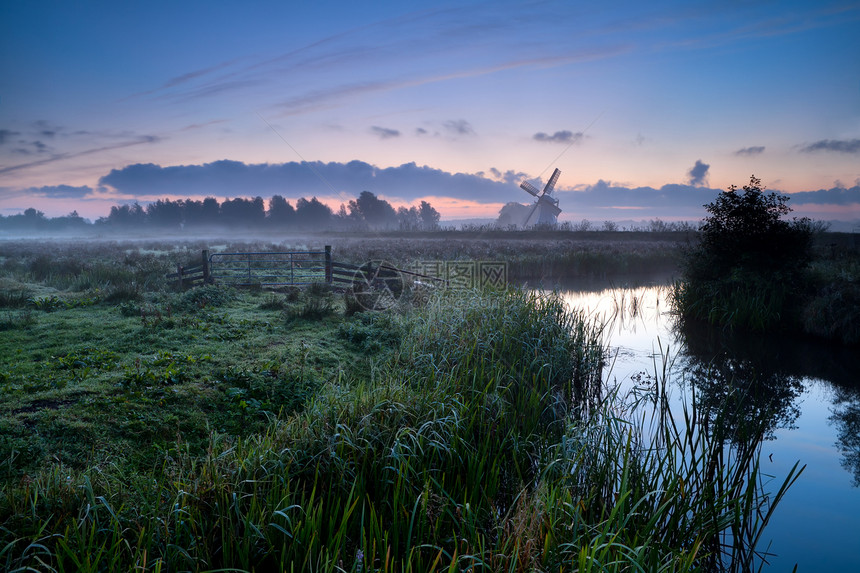 清晨在荷兰农田上沉浸着风车和河水图片