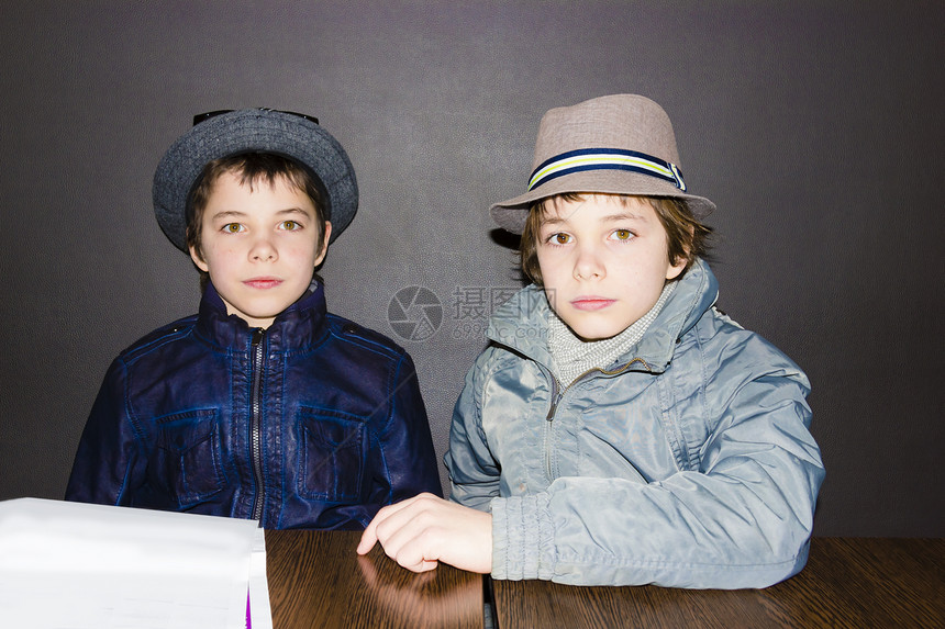 两个男孩在咖啡厅的桌子上戴帽子图片
