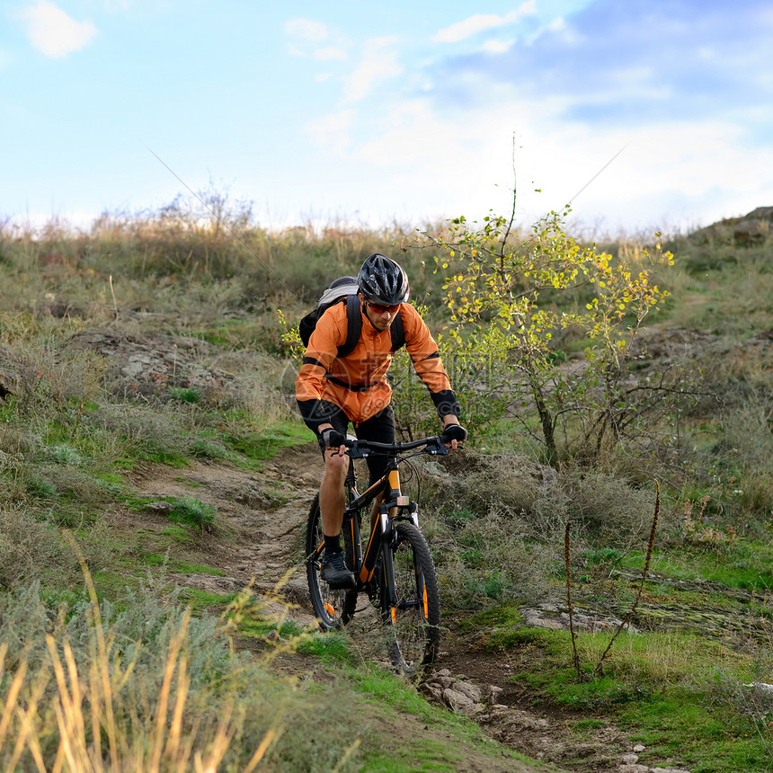 在美丽的山道上骑自行车的赛车女运动员运动骑士车轮蓝色男生速度岩石娱乐天空竞赛图片