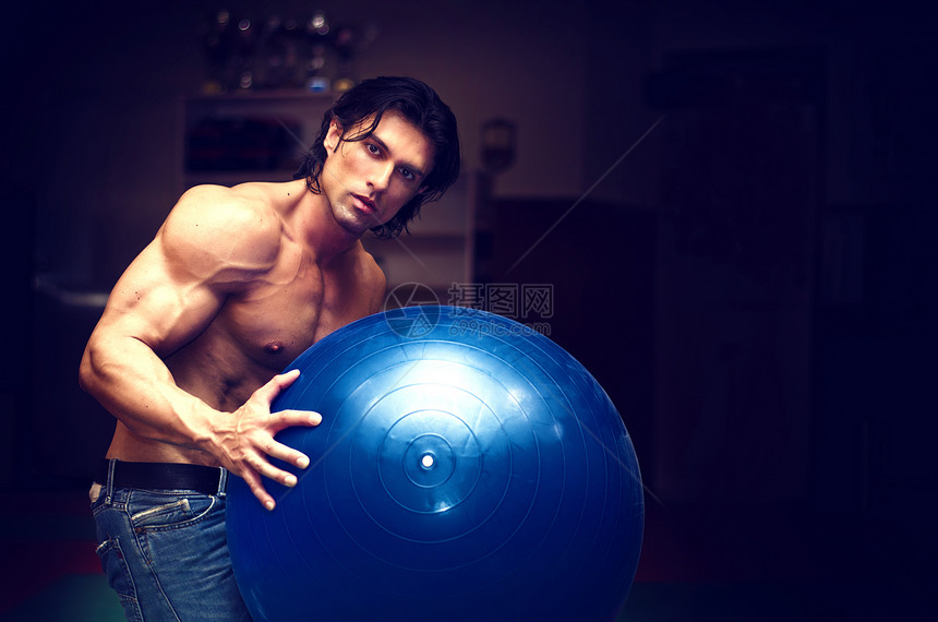 手持健身球的无衬不穿体格的肌肉年轻男子图片