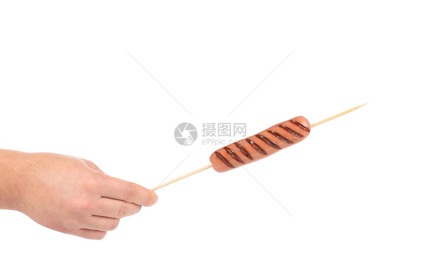 香肠卷在手握的棍子上烤焦了图片