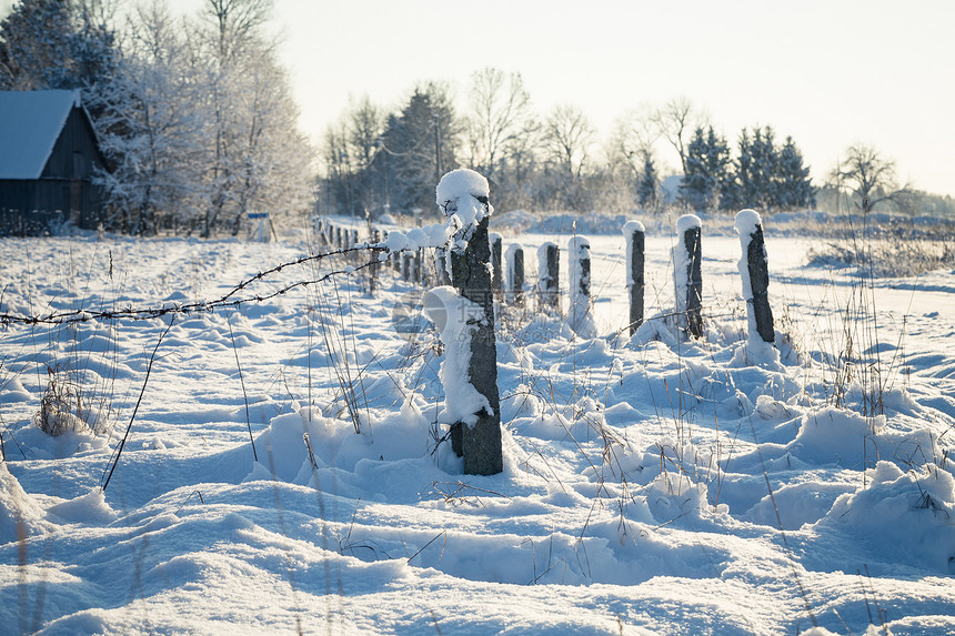 带雪覆盖地面的刺铁丝栅栏天空场地脚印蓝色农场调子天气铁丝网漂移乡村图片