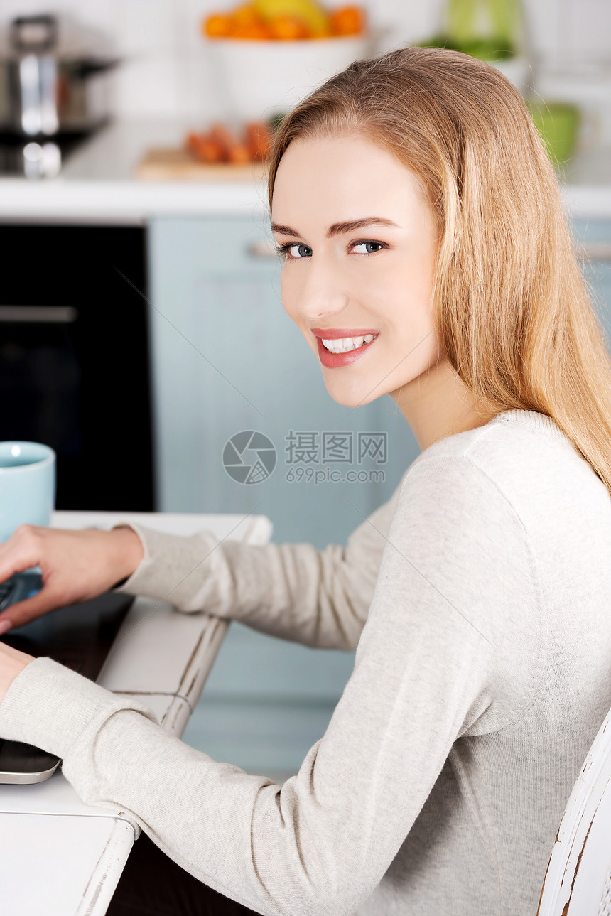 年轻的美女坐在桌子边 用笔记本电脑和杯子商务人士商业网络女孩技术快乐咖啡饮料工作图片