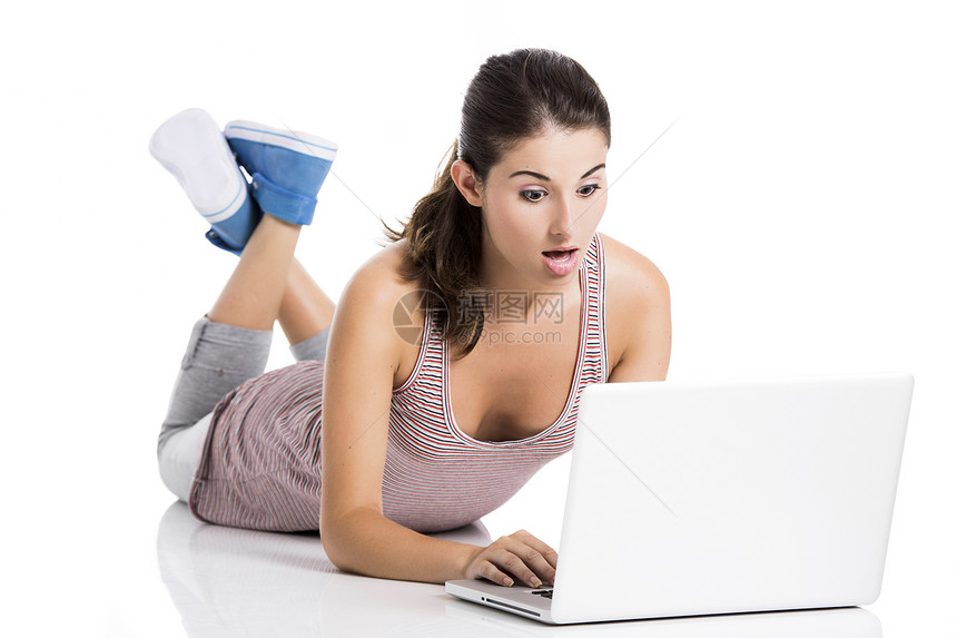 在笔记本电脑上工作的学生微笑学习地面娱乐说谎白色女孩互联网快乐青少年图片