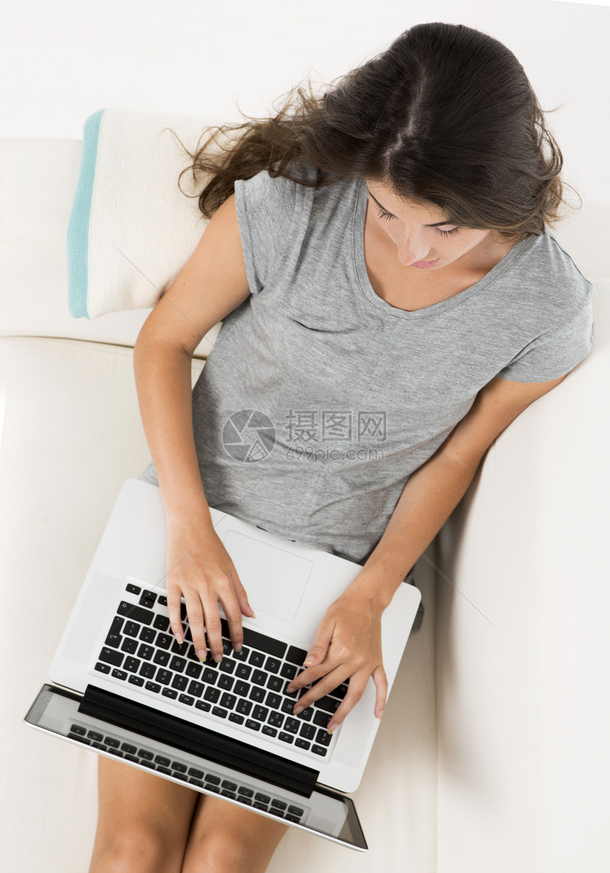 在家用笔记本电脑工作喜悦女孩闲暇黑发白色沙发幸福长椅房子图片
