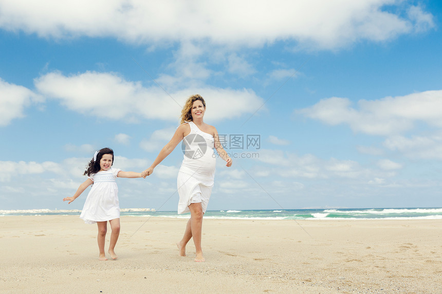 在海滩上散步幸福女性天空童年女孩乐趣家庭成人父母母亲图片