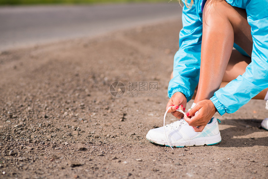 年轻女子在运动鞋上系鞋带力量朋友们蓝色赛跑者自由行动锻炼海滩成人活动图片