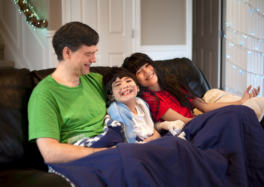 有残疾男孩的家庭在皮革沙发上一起放松图片
