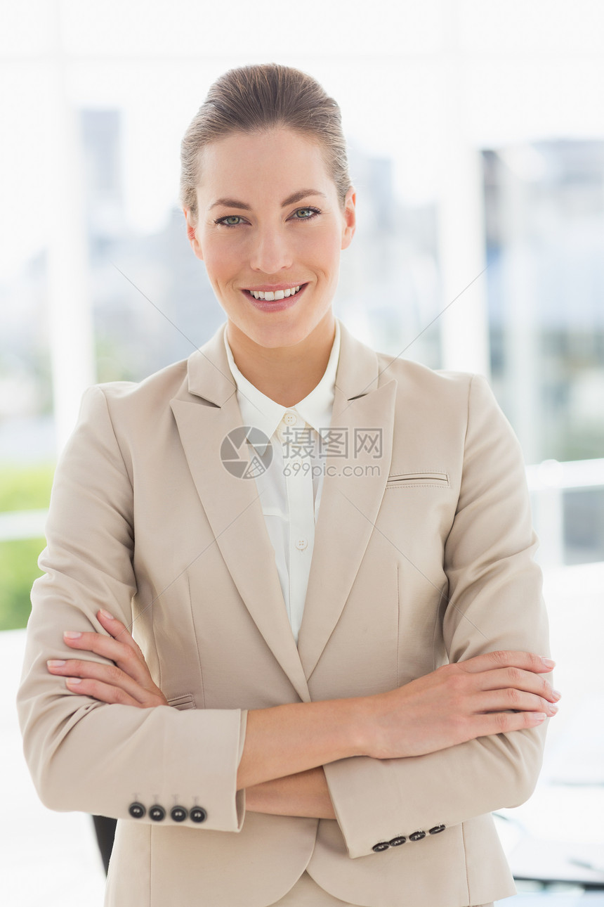 一个年轻女商务人士的肖像 带着双臂穿过微笑图片