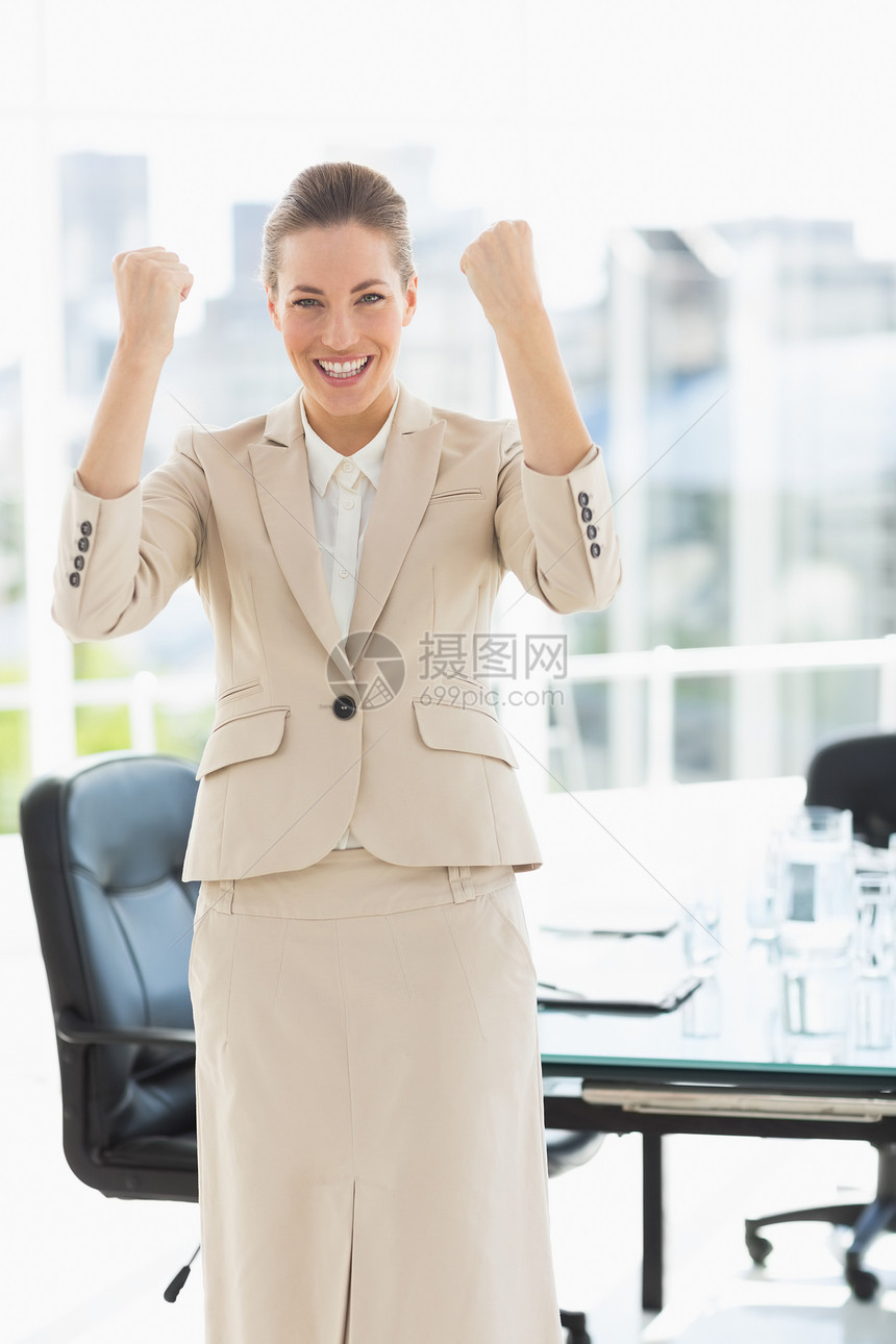 勤劳的女商务人士握着拳头套装快乐成功人士胜利女性女士椅子商务桌子图片
