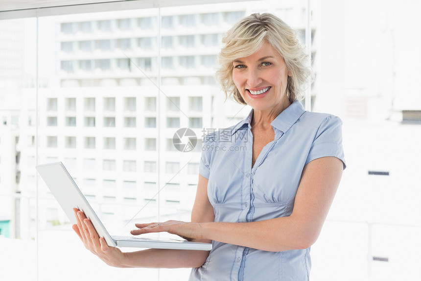 一位使用笔记本电脑的快乐女商务人士的肖像图片