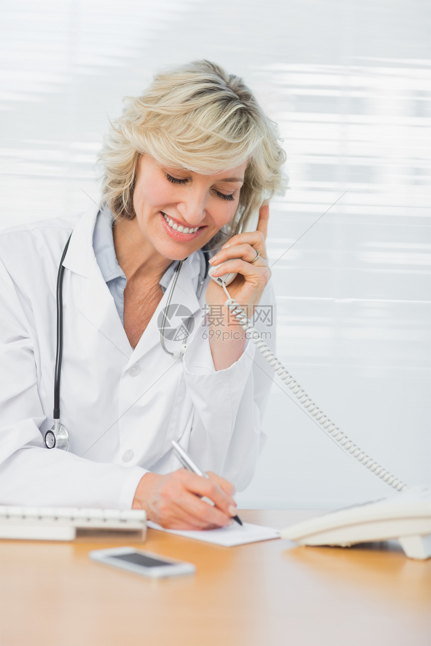医生在医务室写笔记时使用电话职场桌子女性医疗保健键盘服务沟通固定电话保健头发图片