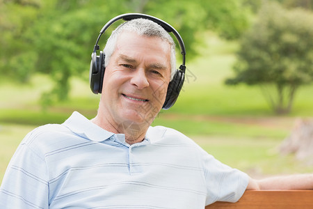 在公园里用耳机微笑的老人背景图片