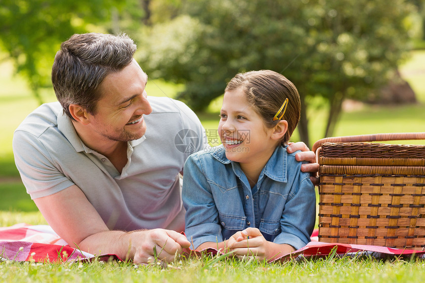 微笑的父亲与年轻的女儿 在公园的草地上躺在草地上图片