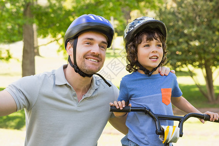 微笑的男人和他儿子一起骑自行车背景图片