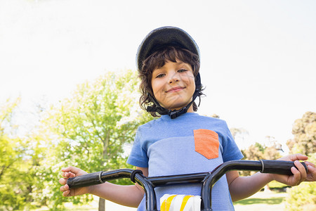 骑自行车的小可爱男孩男性学习农村享受微笑公园天空乐趣安全头盔背景图片