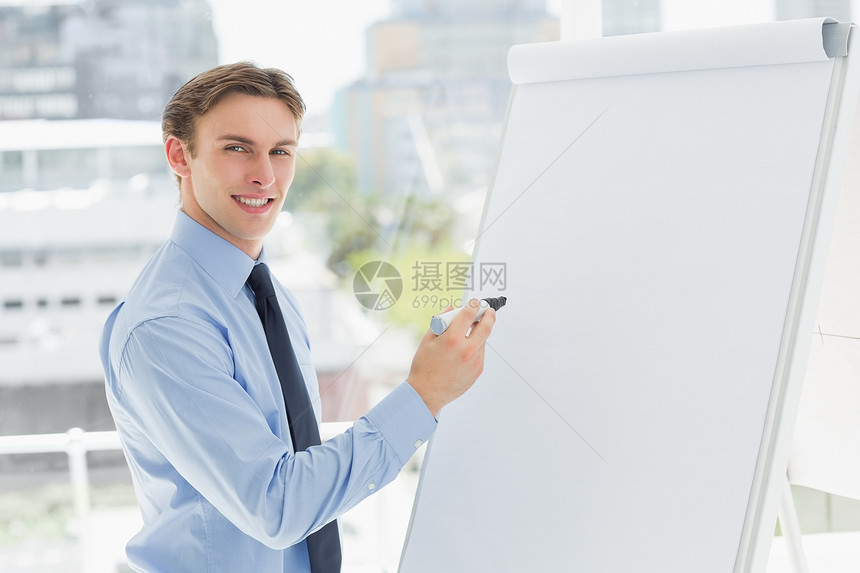 年轻笑笑的商务人士在白板上用标记写字图片