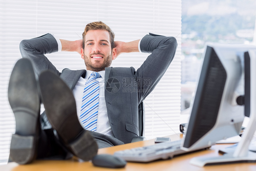 坐在桌子上双腿坐着的业士微笑男性鞋类电脑职场男人职业商业办公室人士图片