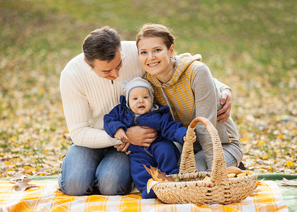 婴儿随拍年轻夫妇和小男孩在秋天野餐背景