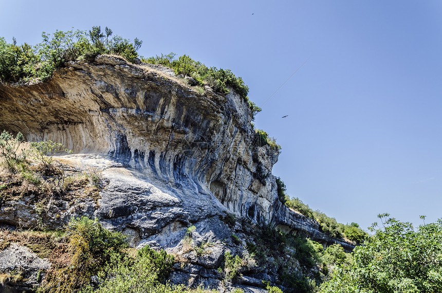 美丽的岩石天空悬崖阴影蓝色环境拥抱绿色丘陵爬坡摄影图片